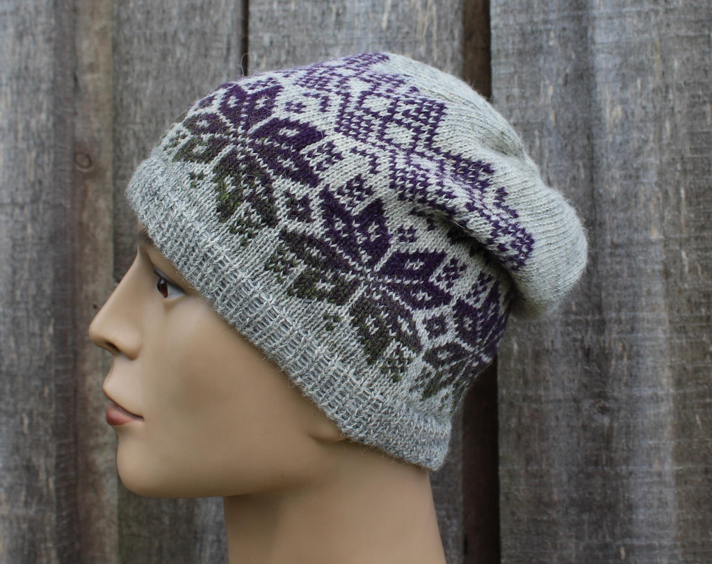 Knitted hat with a purple and green pattern on a mannequin head against a wooden background