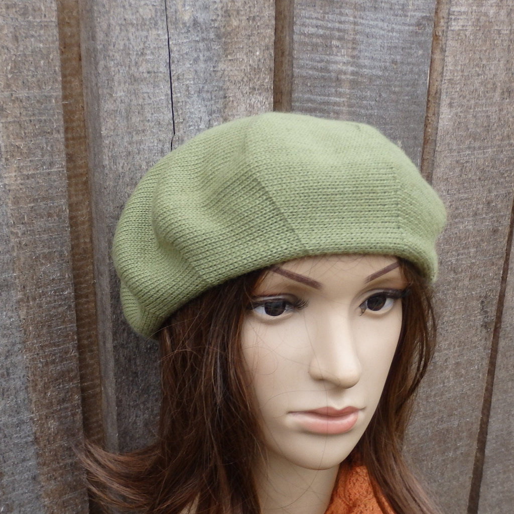 Green knitted beret on a mannequin head against a wooden background