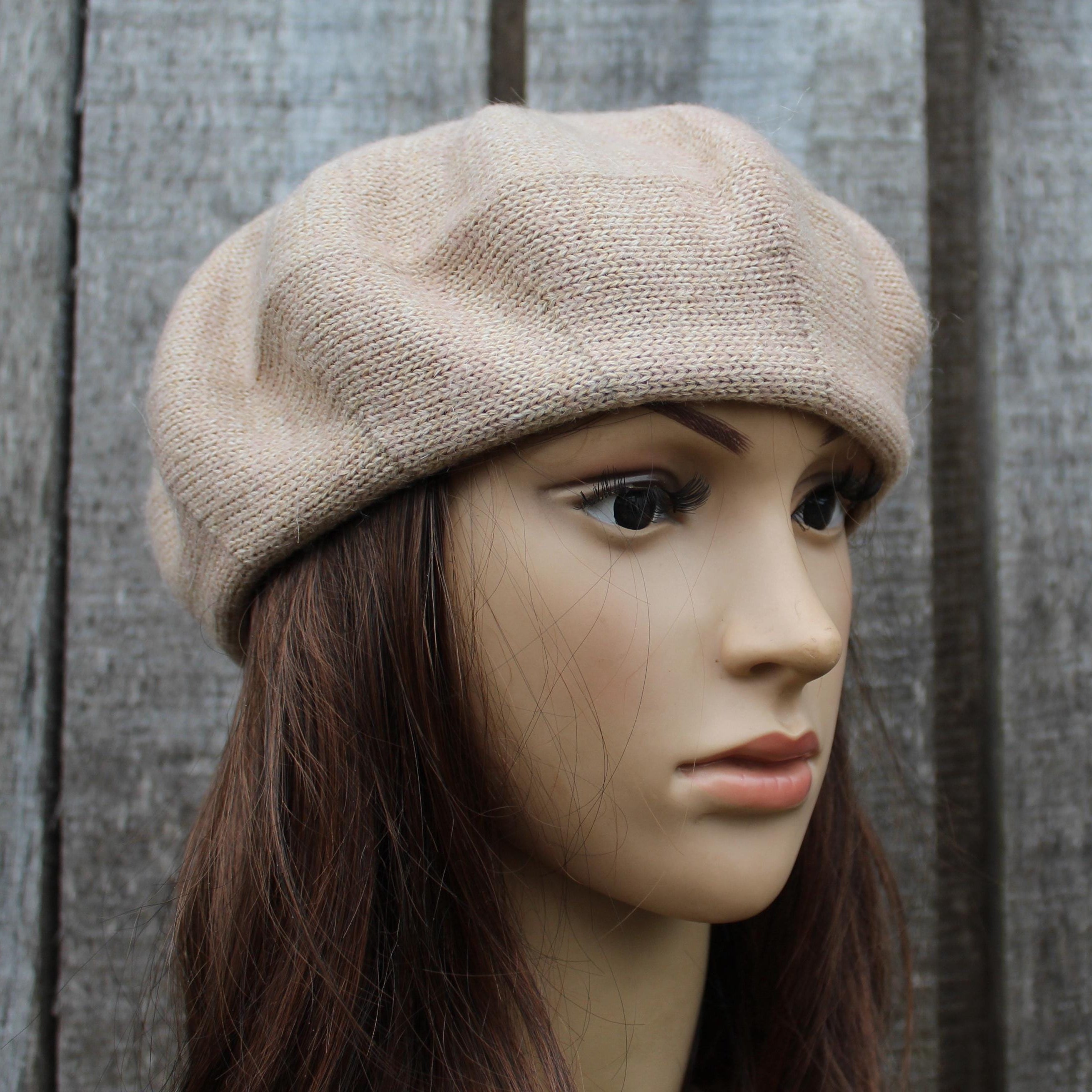 Mannequin head wearing a beige beret against a wooden background