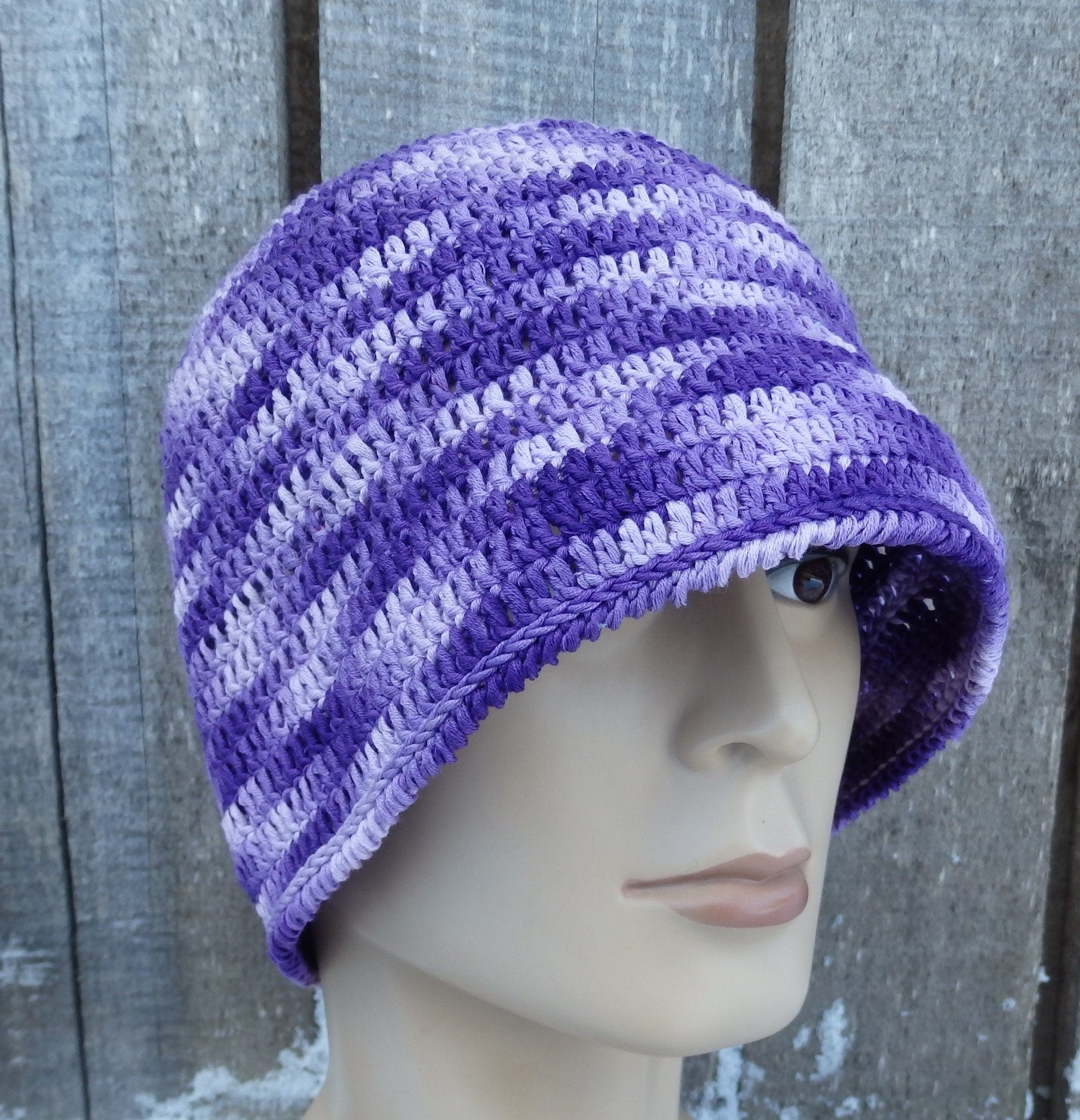 Purple and white striped knit hat on a mannequin head against a wooden background