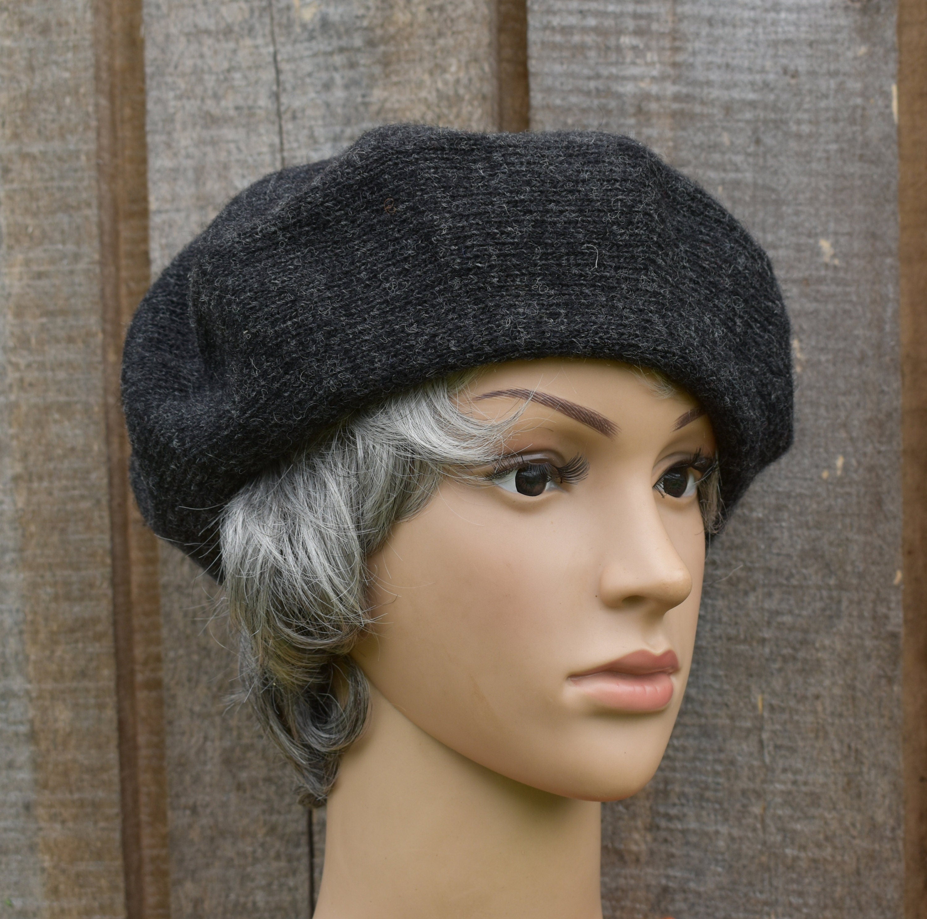 Dark gray beret on a mannequin head against a wooden background