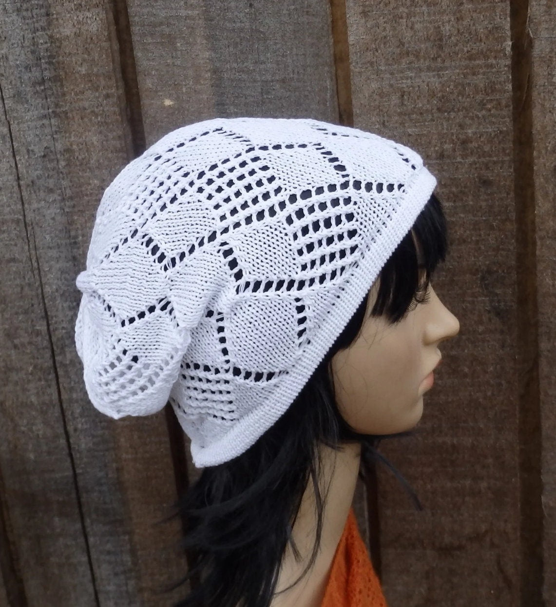 White knitted hat on a mannequin head against a wooden background