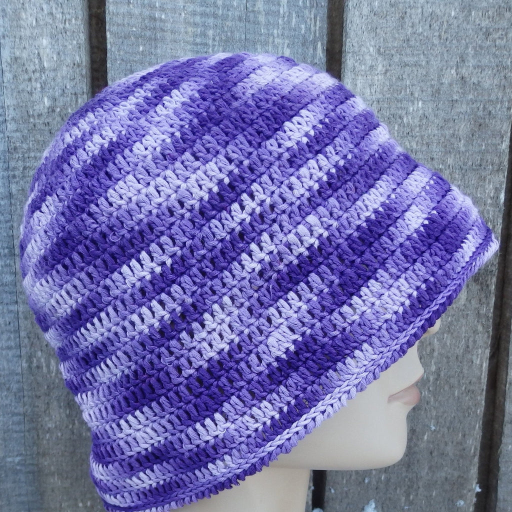 Purple and gray striped crochet hat on a mannequin head against a wooden background