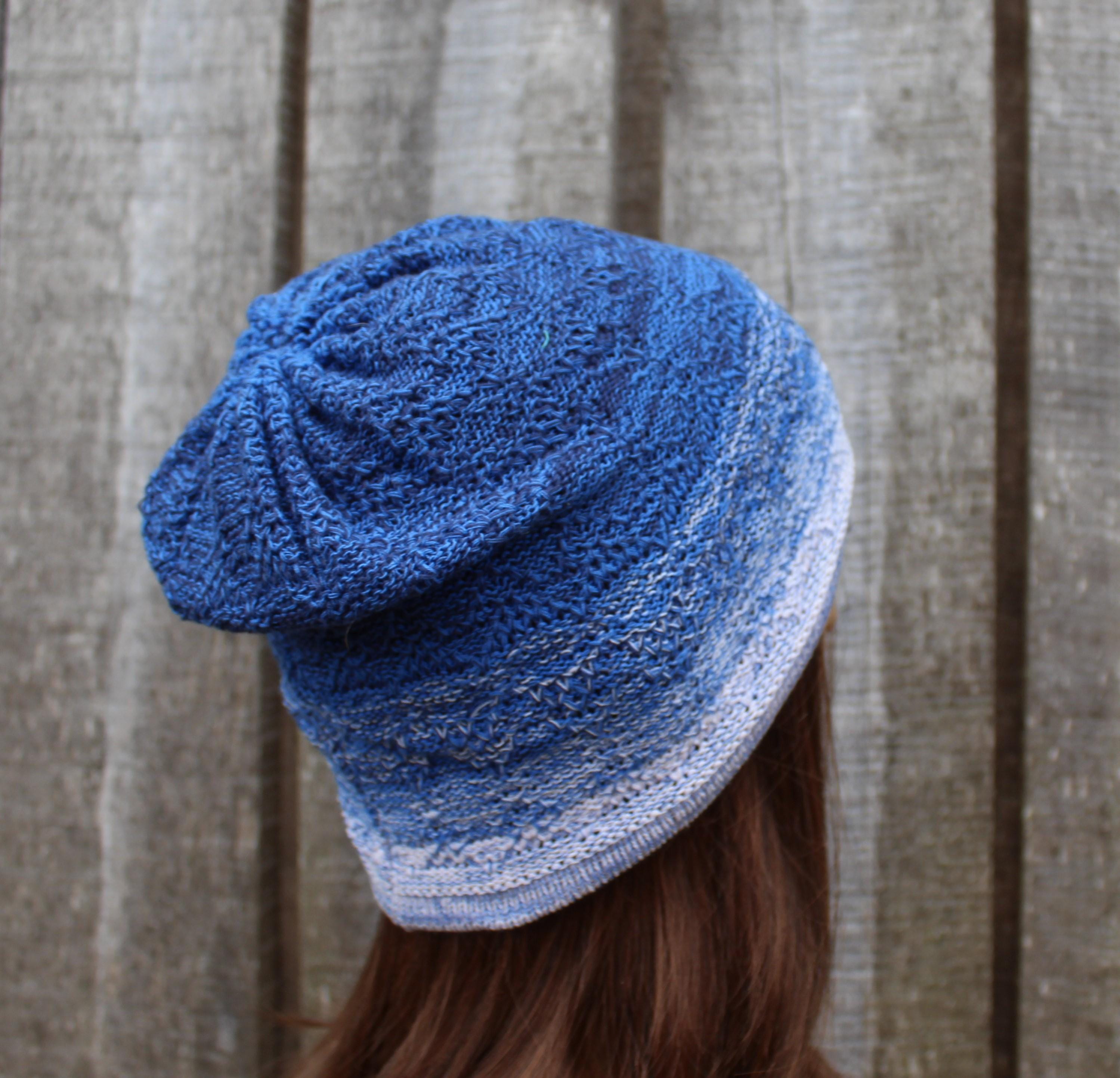 Blue knitted beanie worn by a person against a wooden panel background