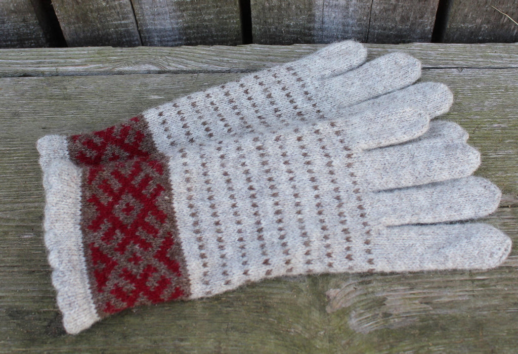 Knitted glove with red pattern on a wooden surface