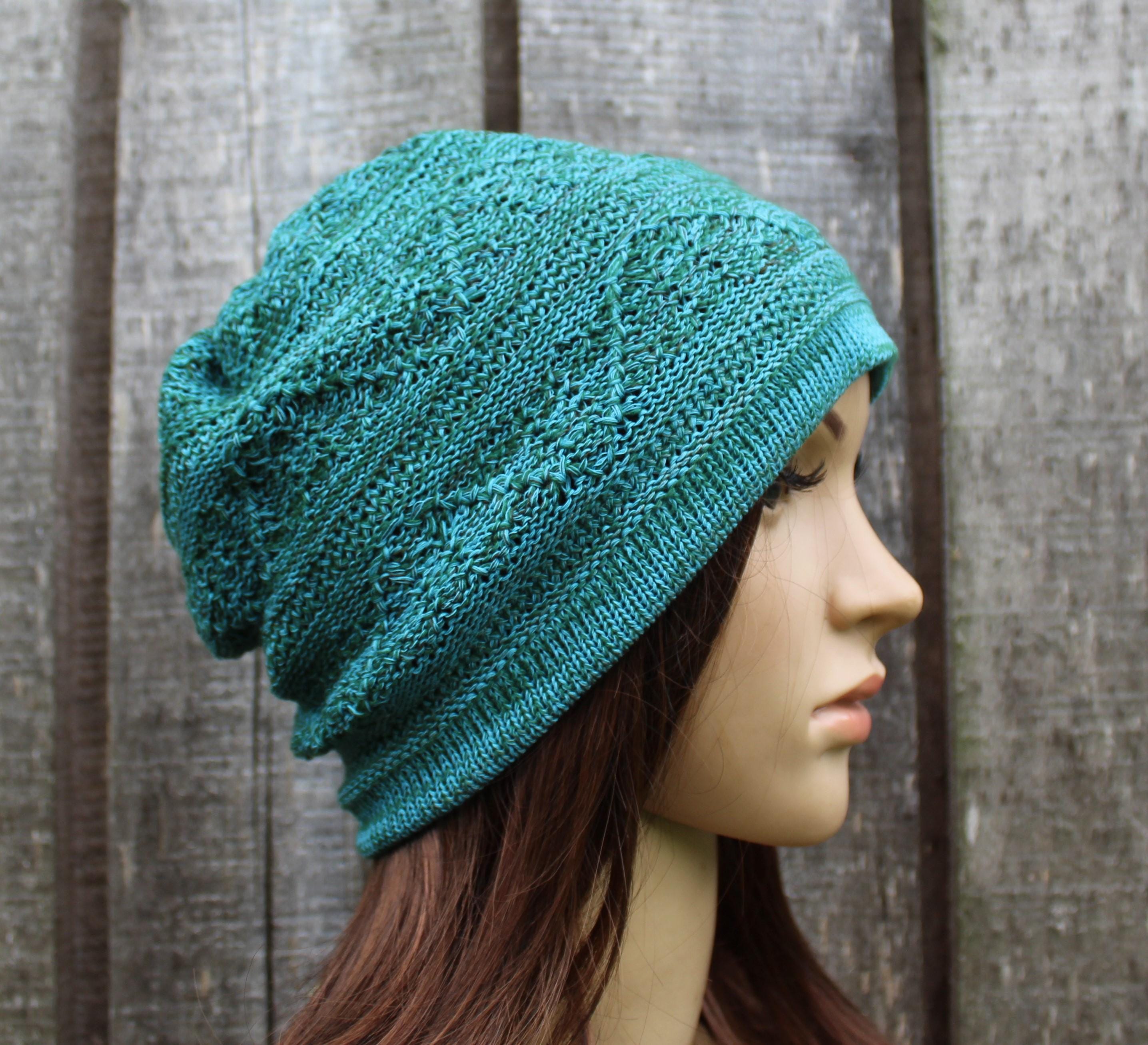 Teal knitted hat on a mannequin head against a wooden background