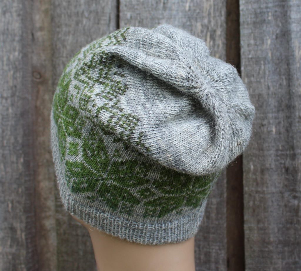 Knitted hat with green and gray pattern against a wooden background