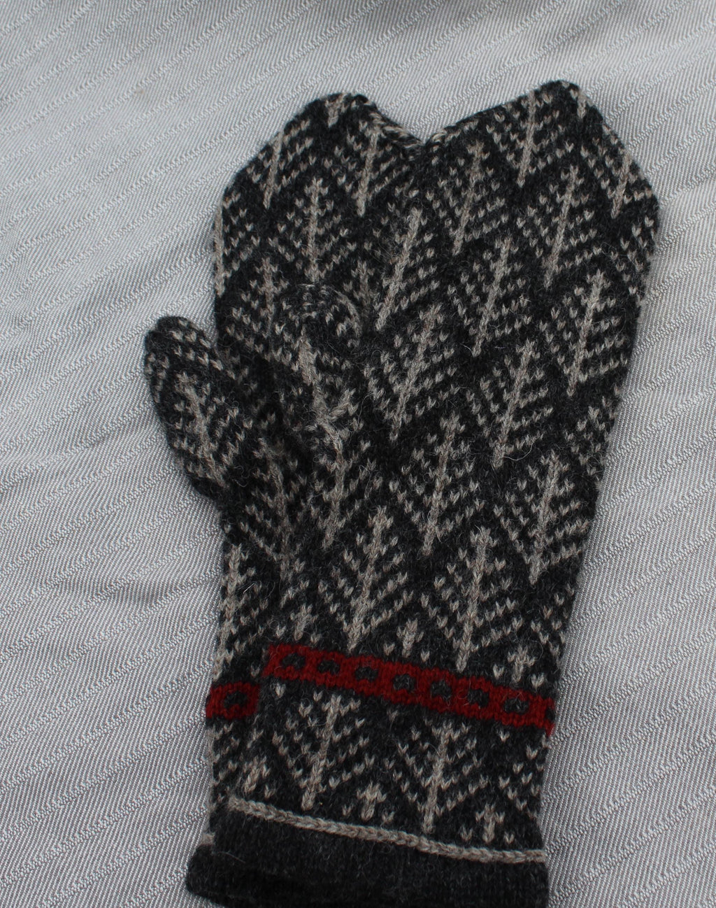 Black and gray patterned glove with red accents on a light gray background