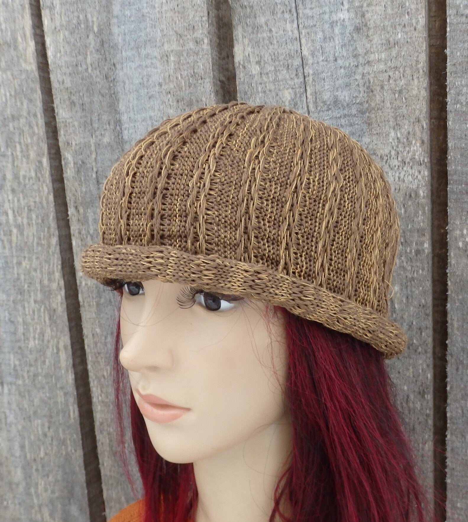 Brown knitted hat on a mannequin head against a wooden background