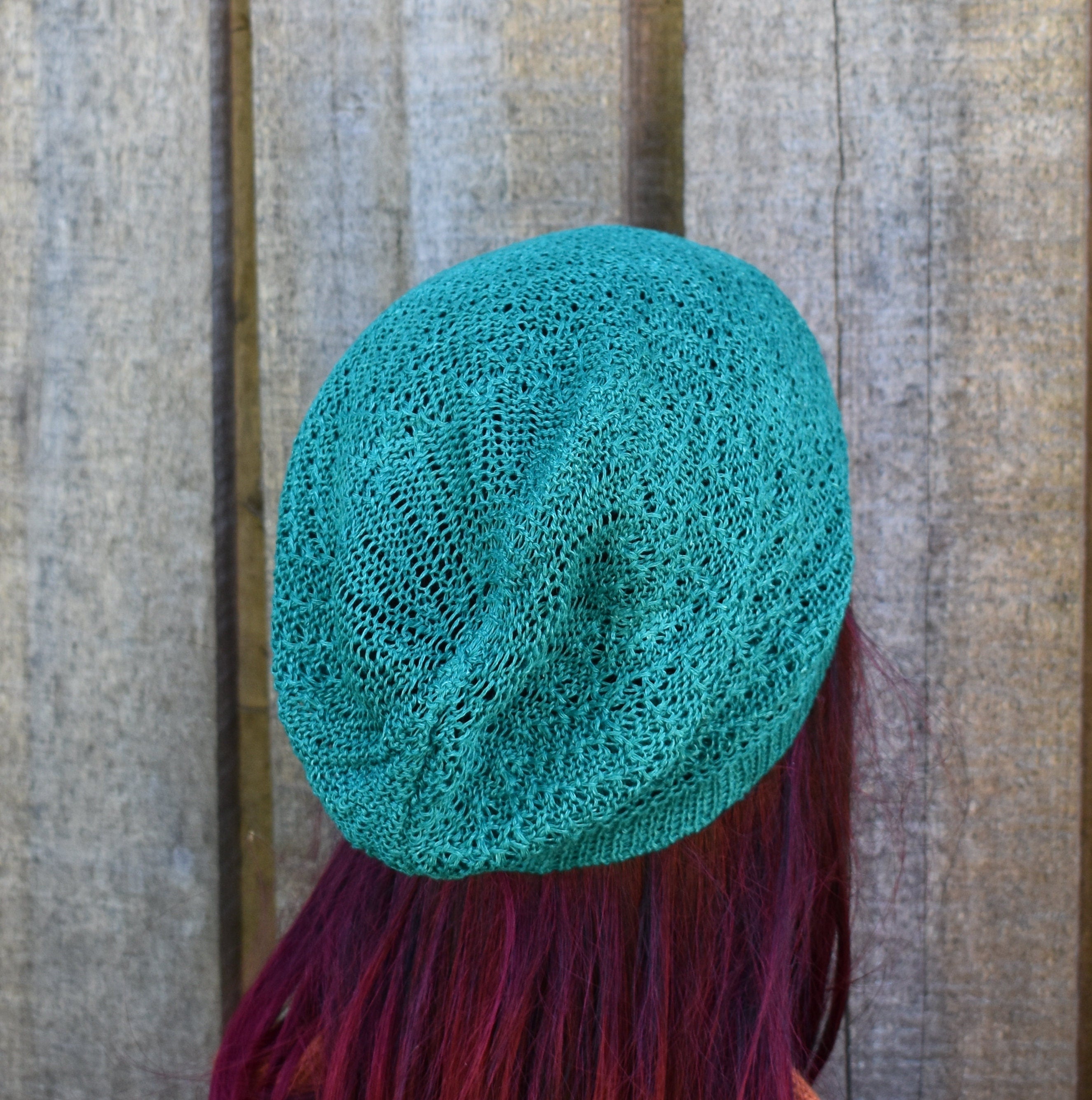 Linen  knitted beanie on a person with red hair against a wooden background