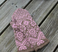 Knitted mitten with a pink and brown pattern on a wooden surface