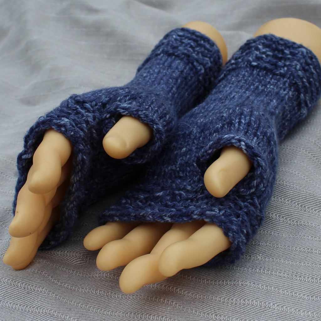 Blue knitted fingerless gloves on a mannequin hand with a gray background
