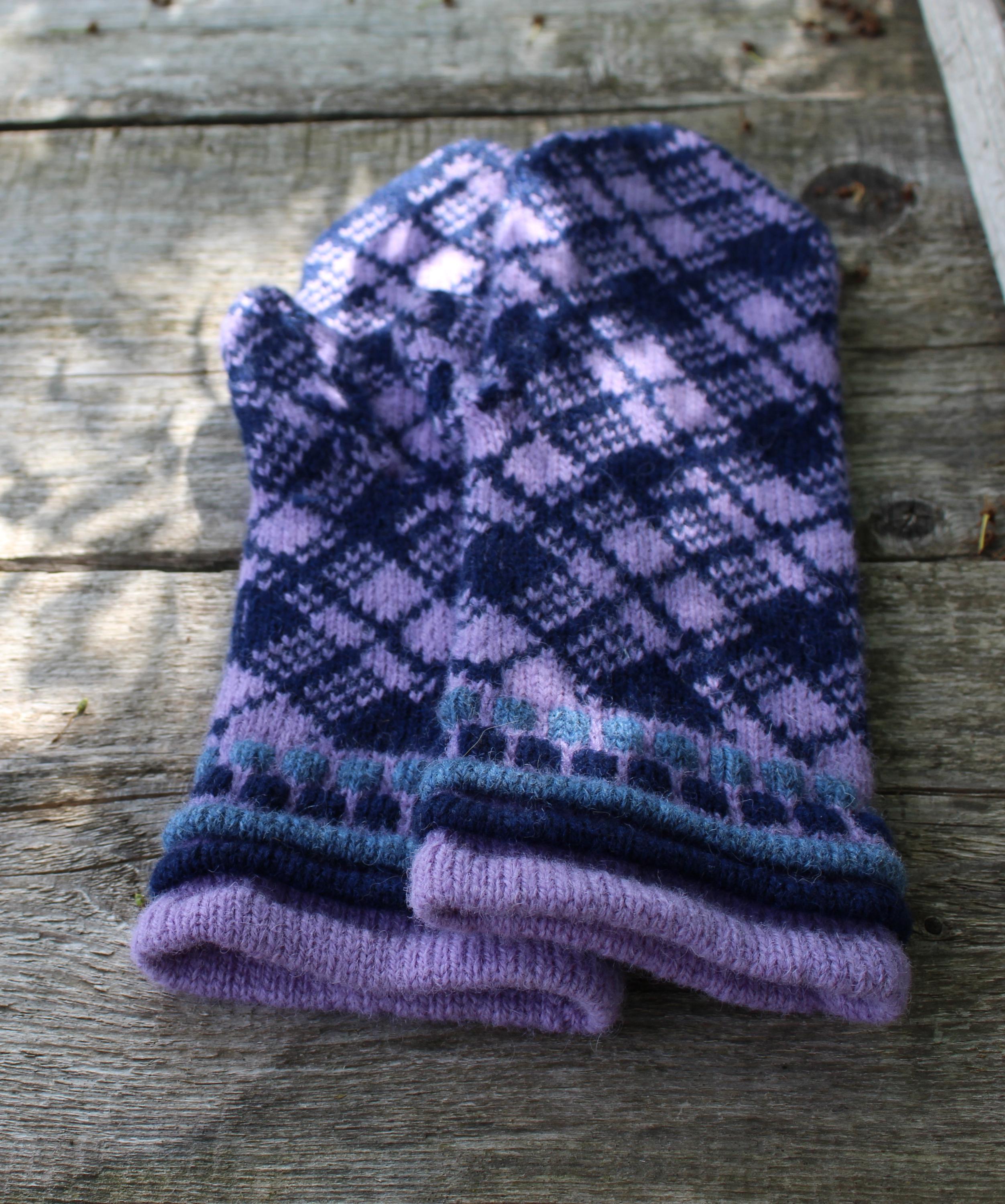 Pair of purple and blue patterned mittens on a wooden surface