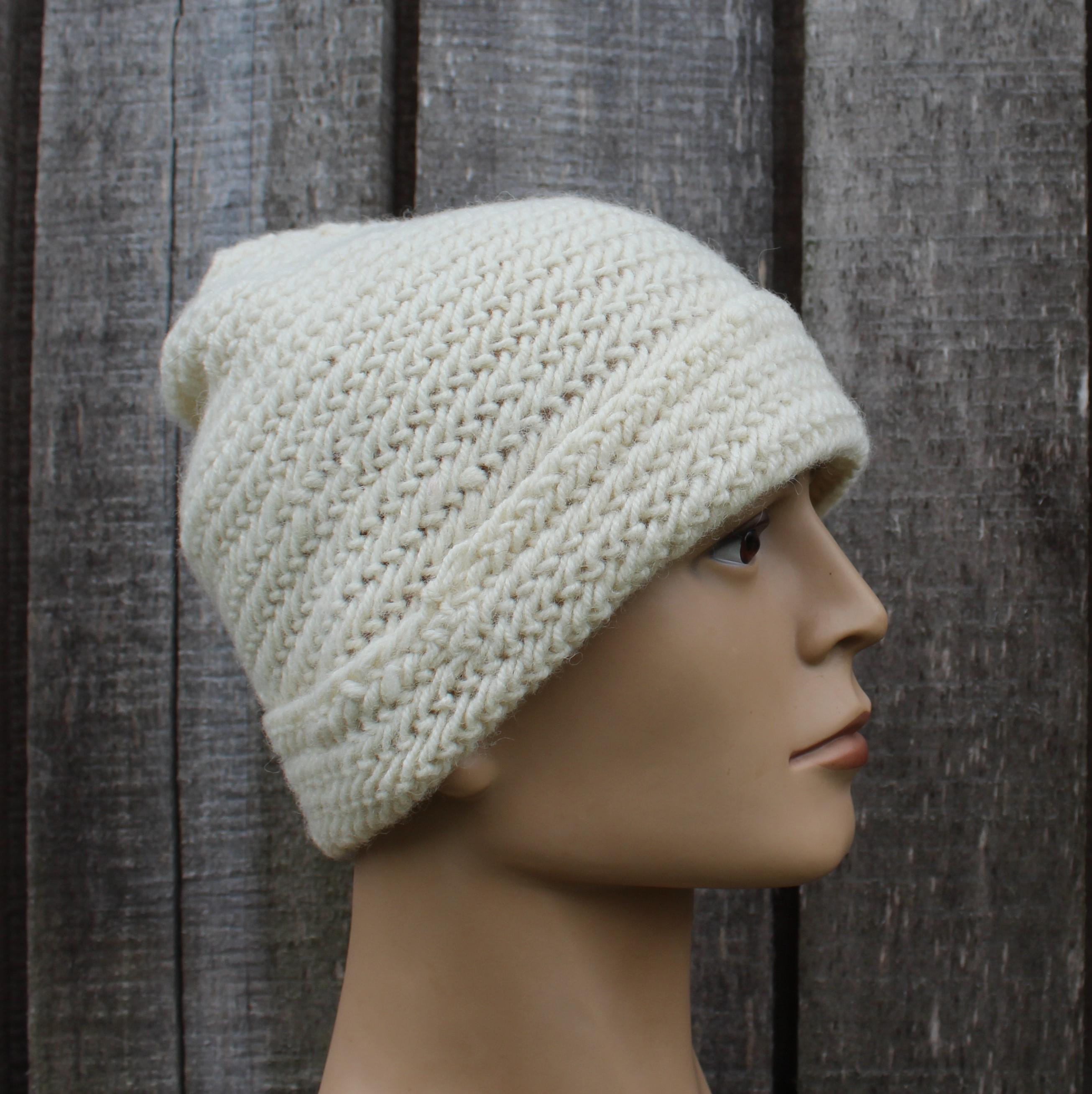 Knitted beige beanie on a mannequin head against a wooden background
