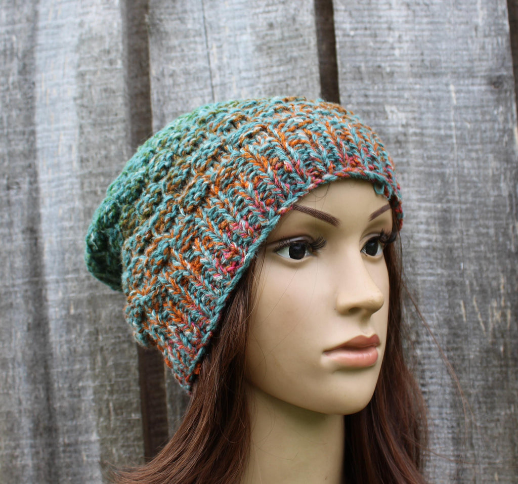Multicolored knitted beanie on a mannequin head against a textured gray background