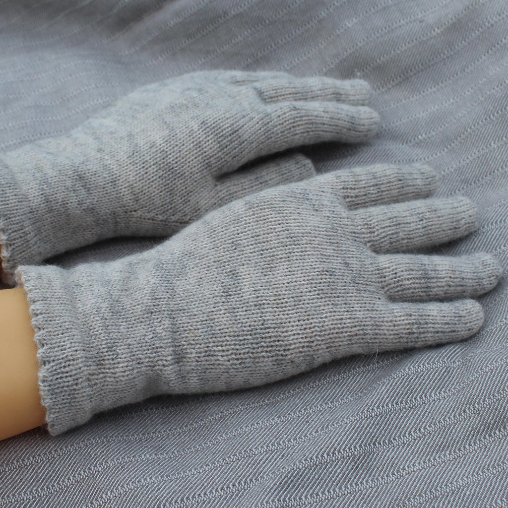 Gray gloves on a person's hands with a gray fabric background