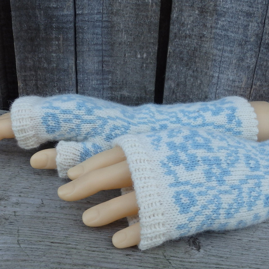 Pair of light blue and white patterned fingerless gloves on a wooden surface