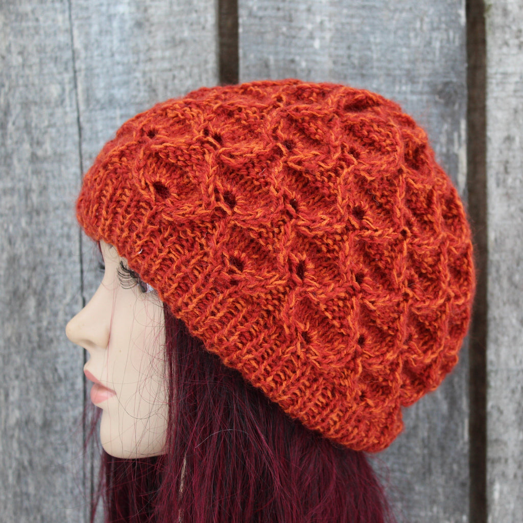 orange knit beanie on a mannequin head against a wooden background