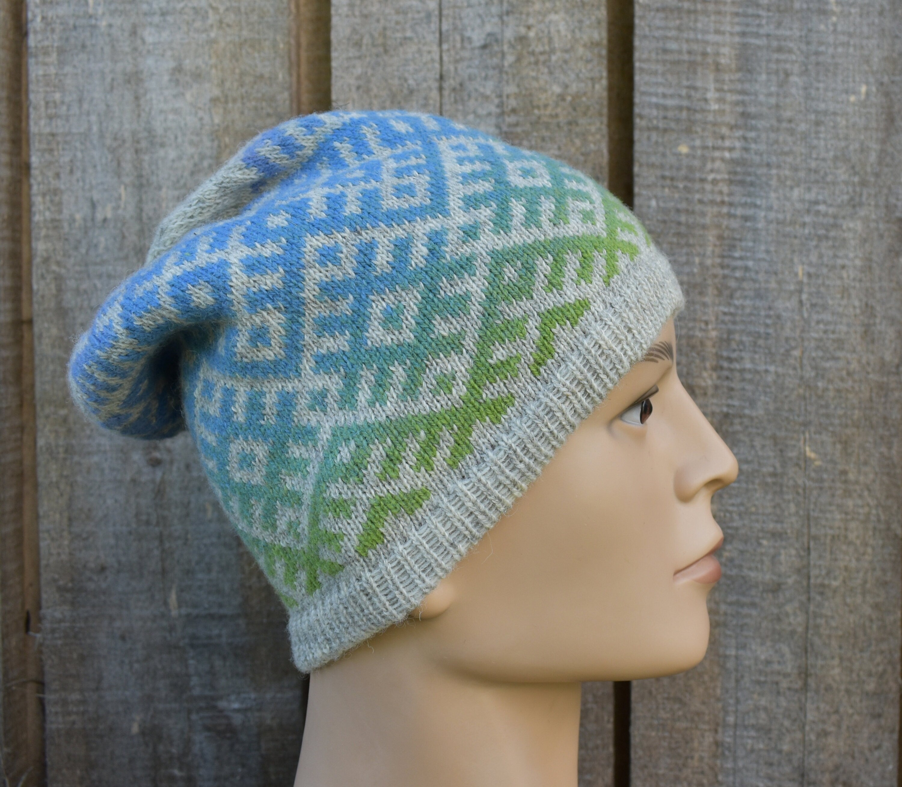 Knitted hat with a pattern on a mannequin head against a wooden background