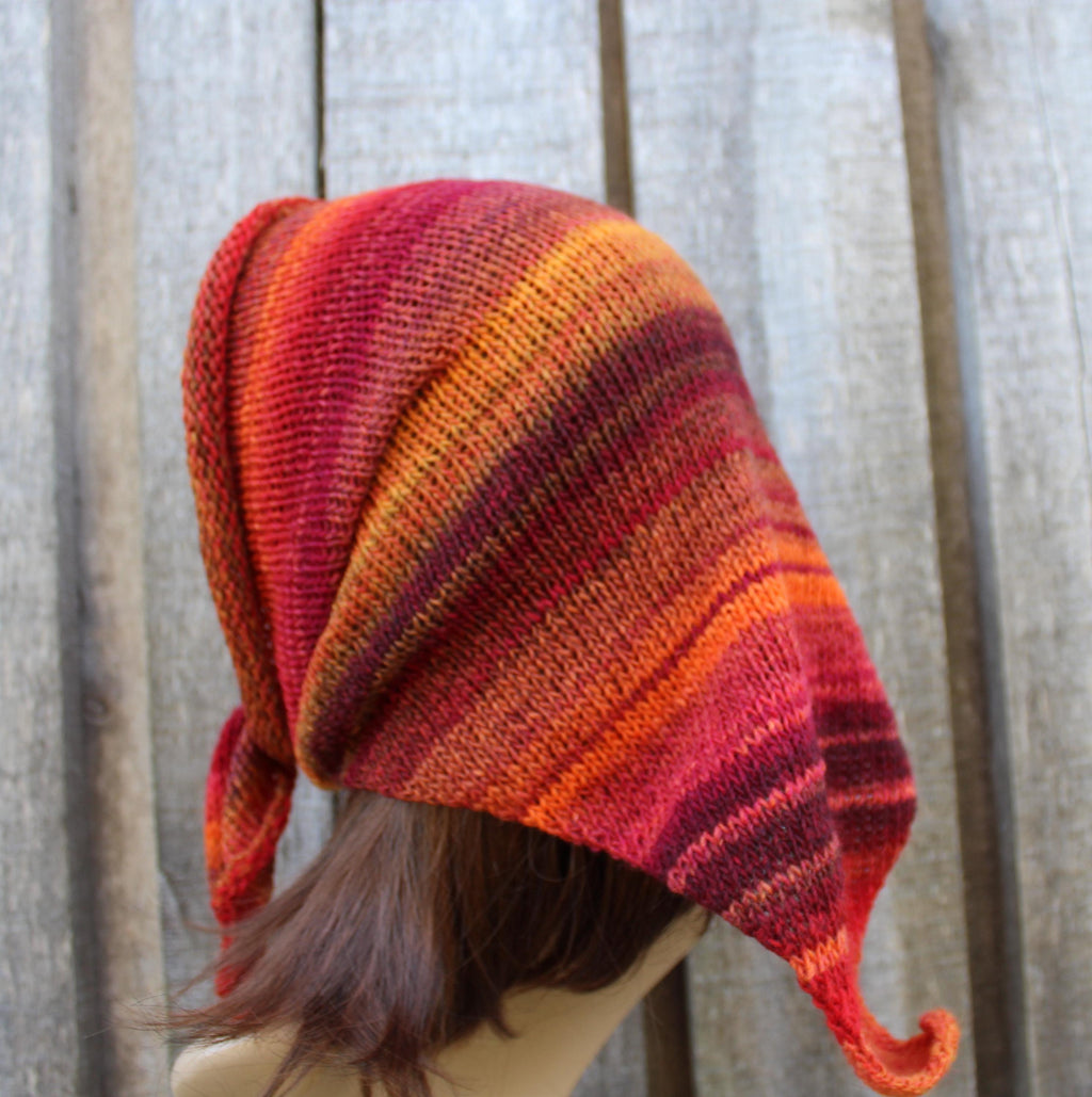 Knitted hat with orange and red stripes on a wooden background