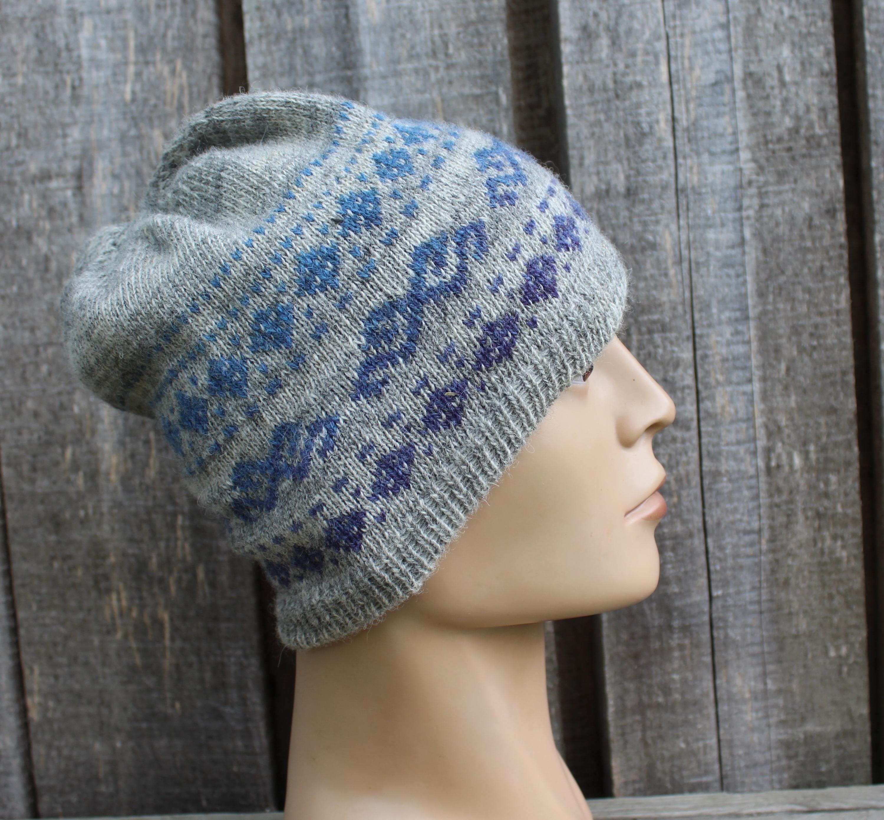 Gray knit beanie with blue floral pattern on a mannequin head against a wooden background