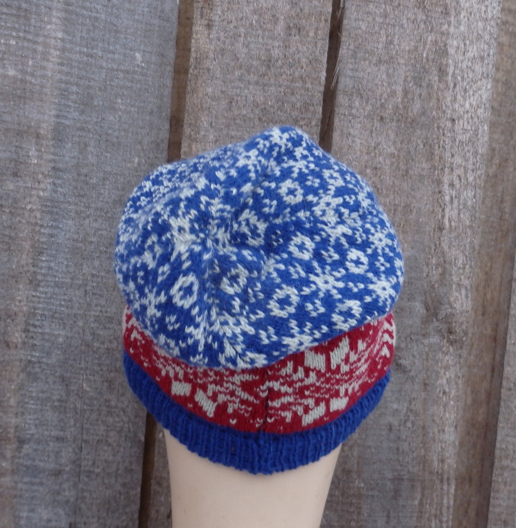 Knitted hat with blue and red pattern on a wooden background