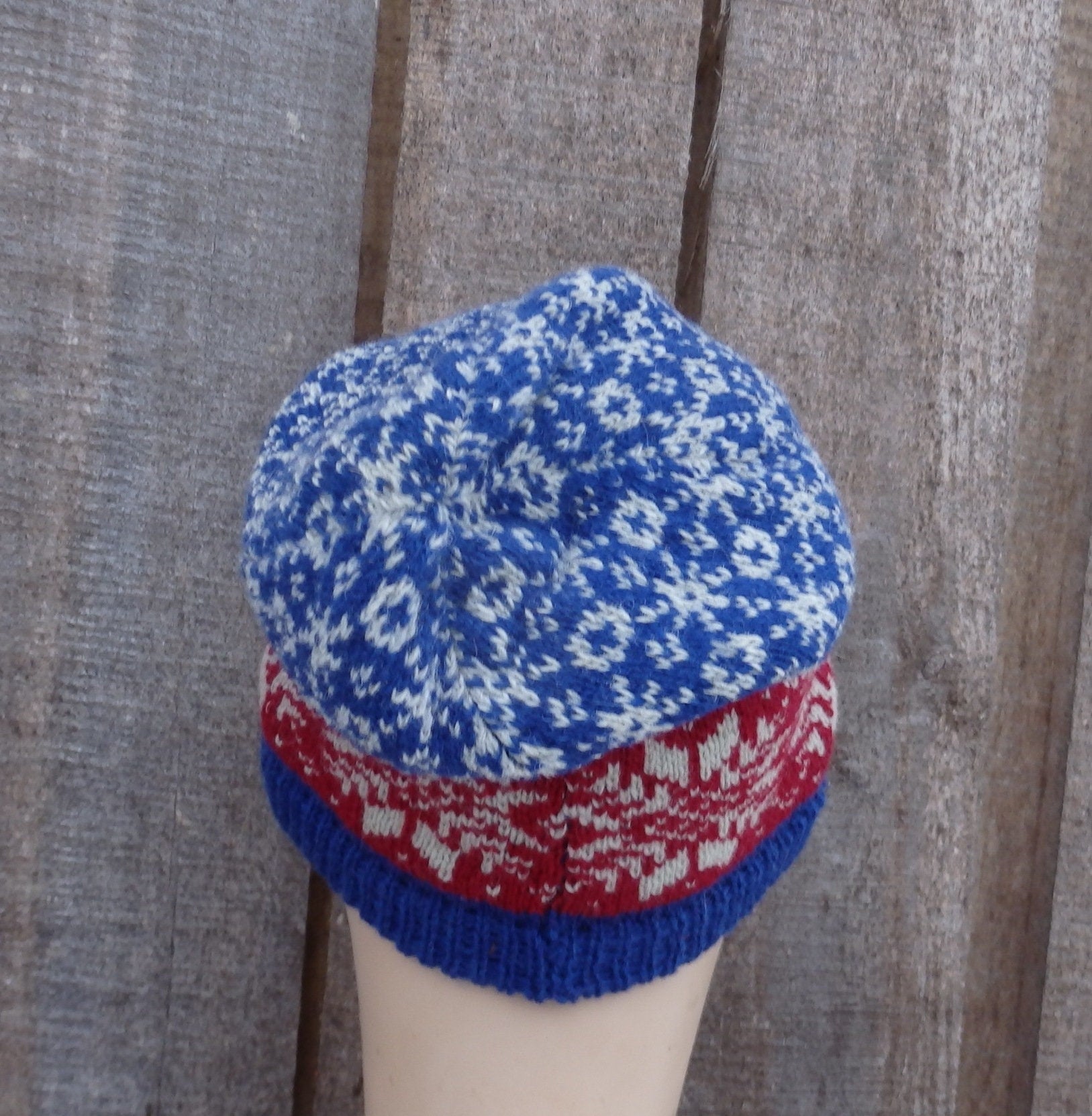 Knitted hat with blue and red pattern on a wooden background