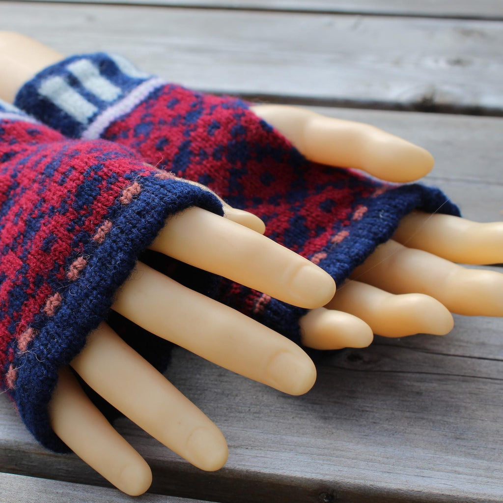 Pair of knitted fingerless gloves on a mannequin hand against a wooden background