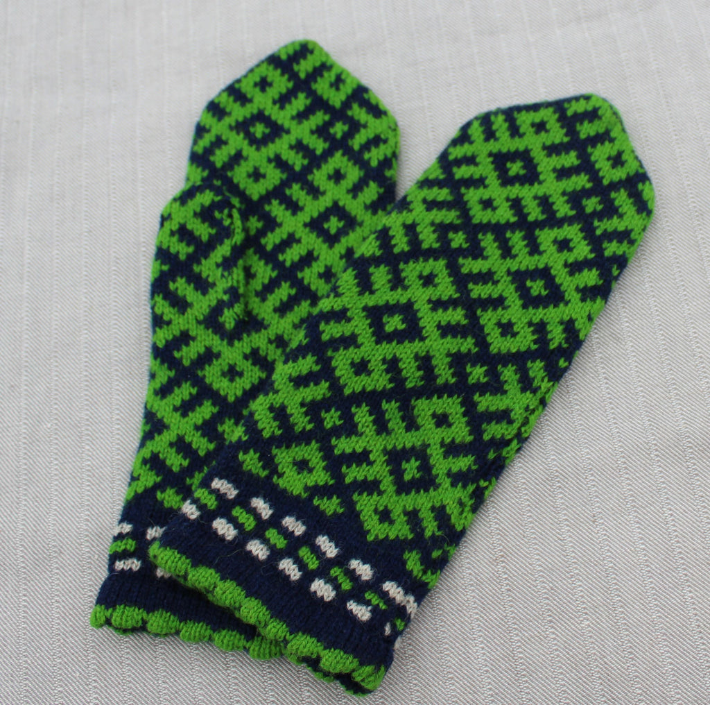 Green and blue patterned mitten on a light gray background