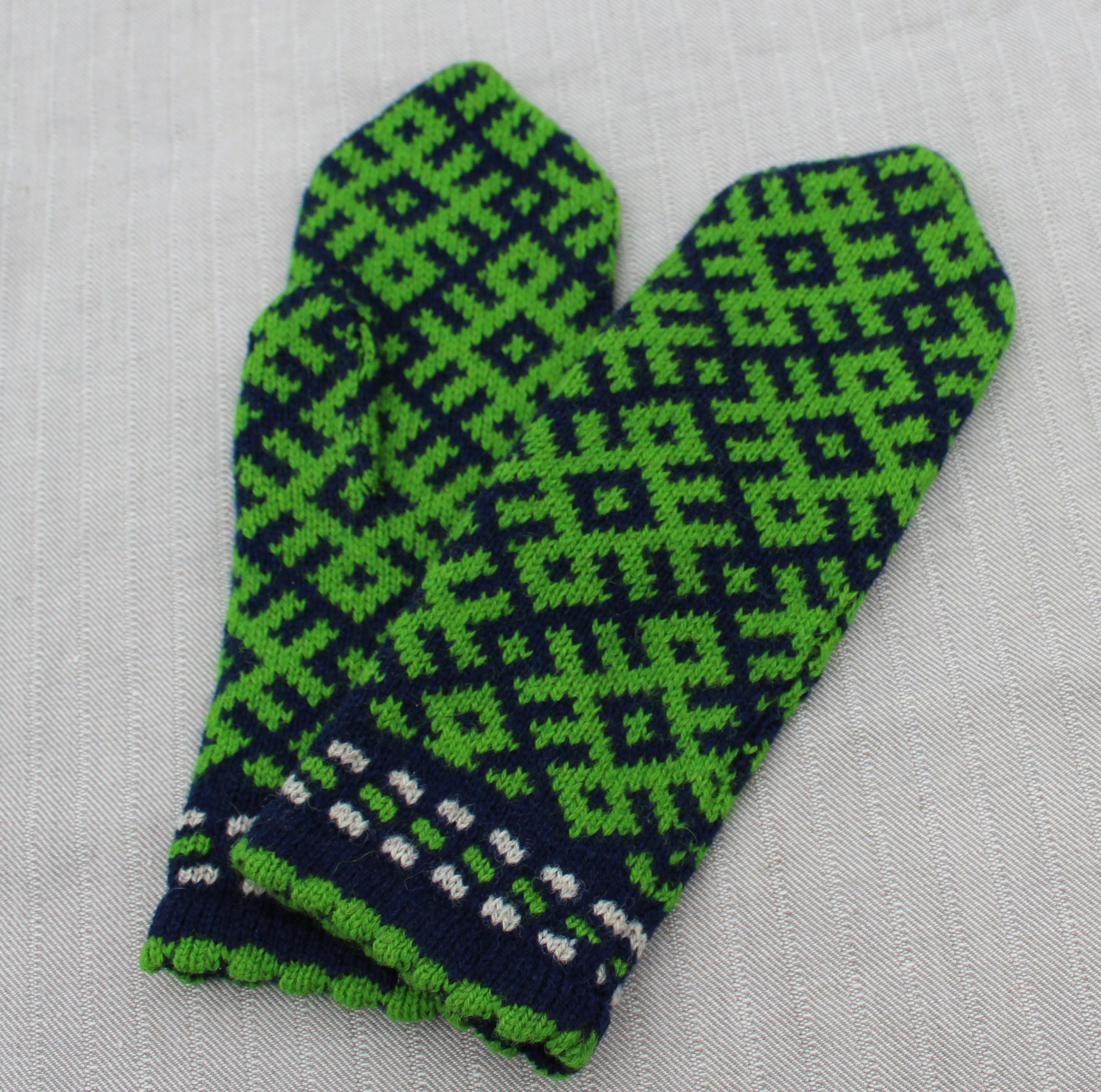 Green and blue patterned mitten on a light gray background