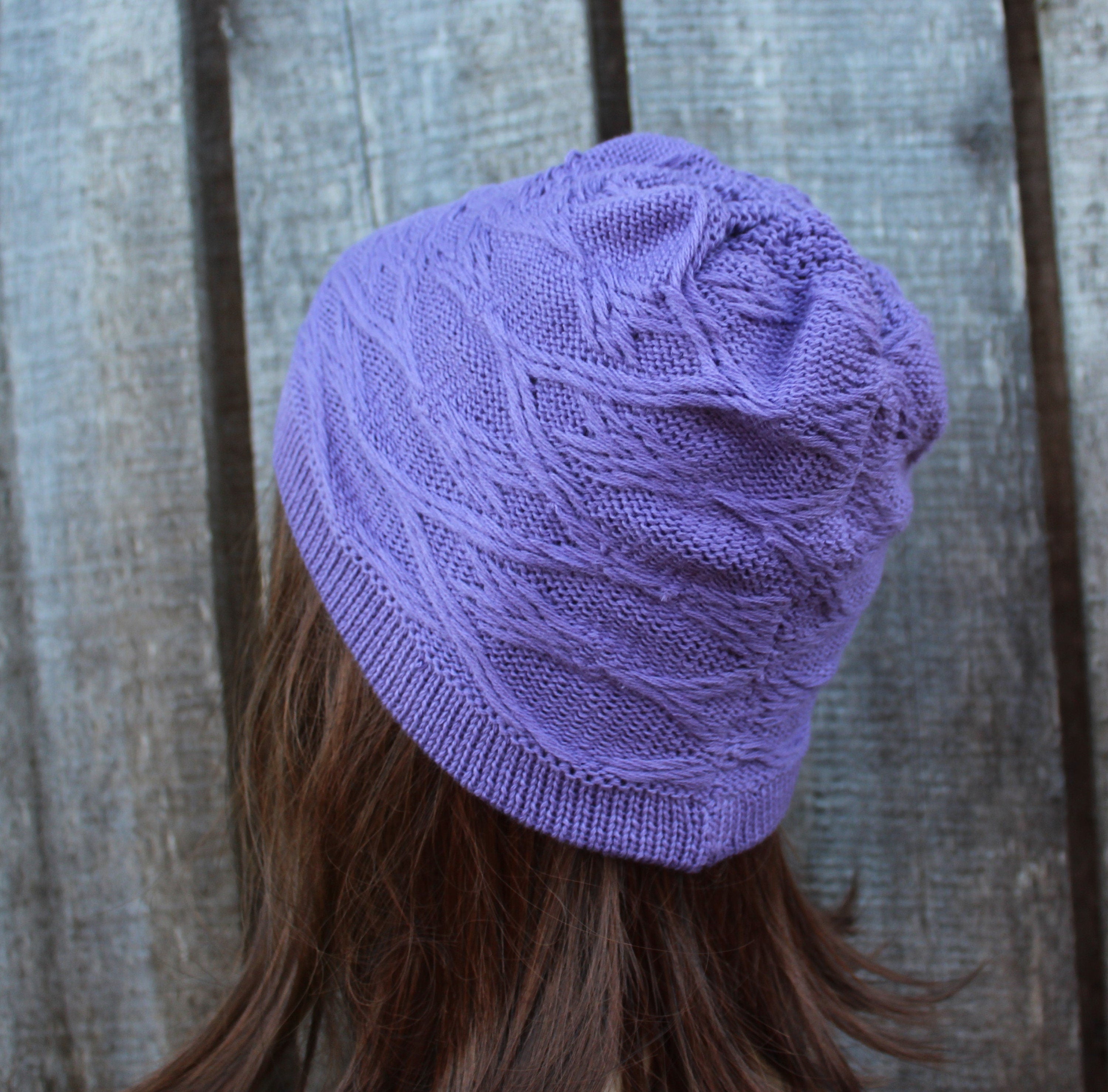 Purple knitted beanie worn by a person with a wooden background
