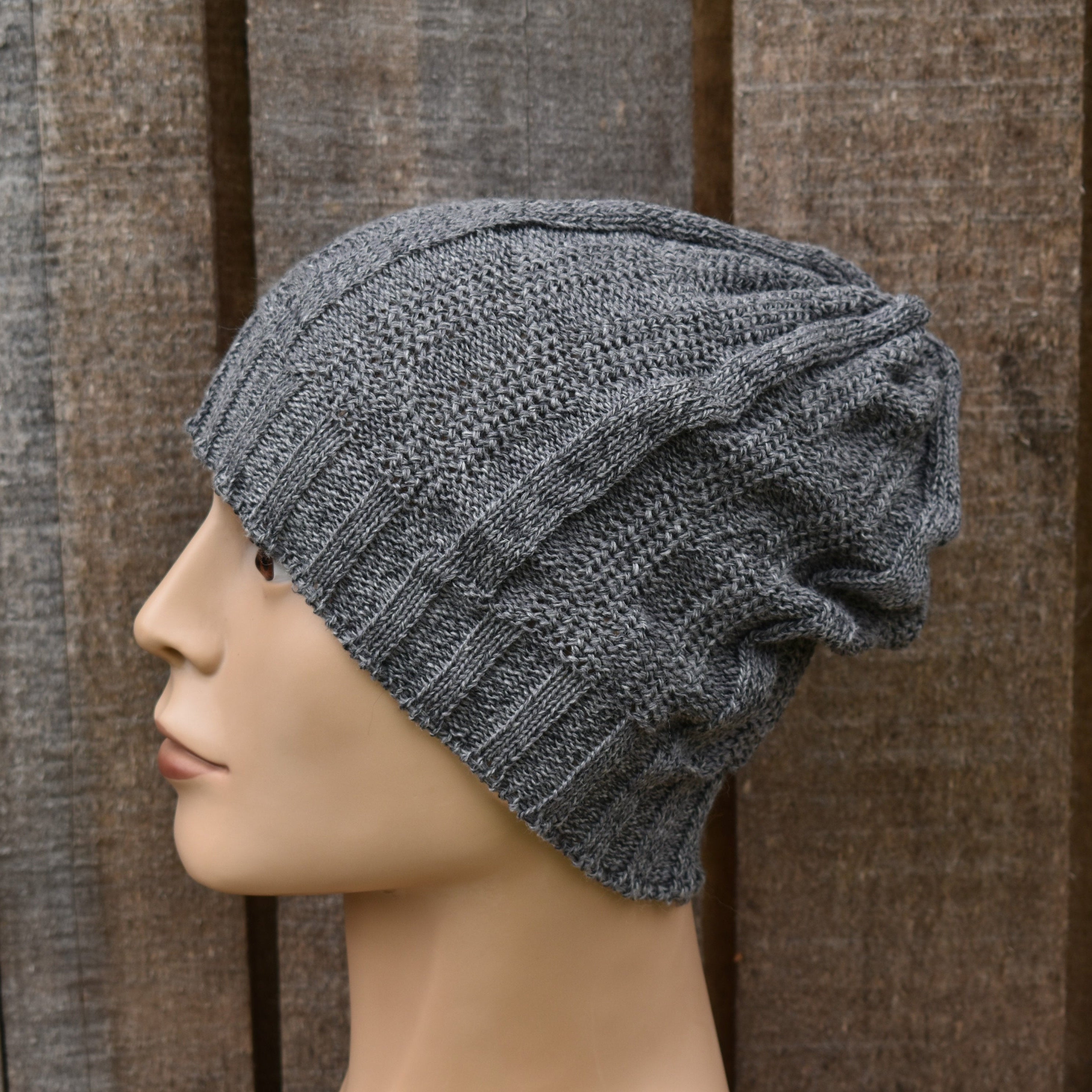 Gray knit beanie on a mannequin head against a brown textured background