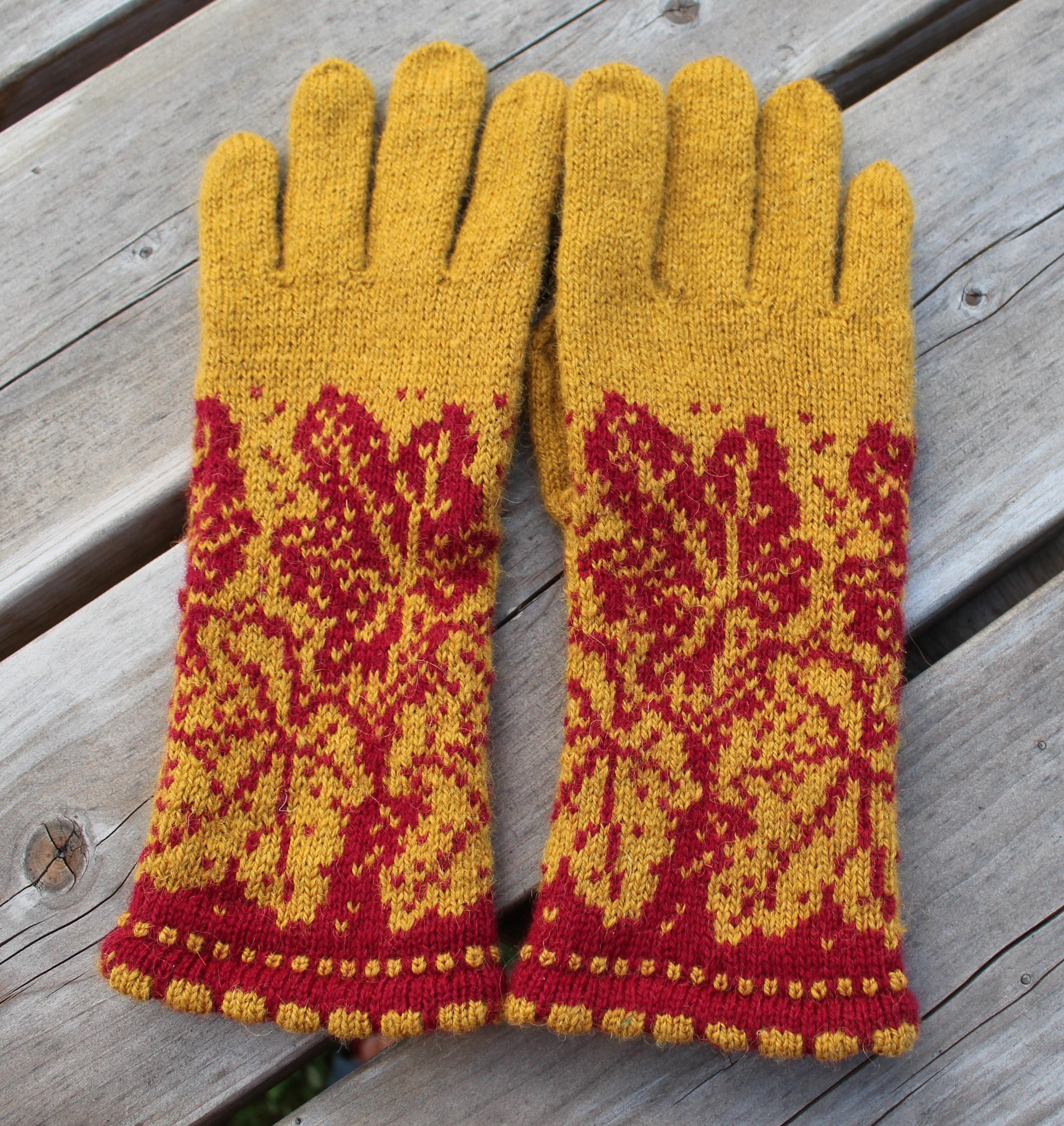 Pair of yellow and red patterned gloves on a wooden surface