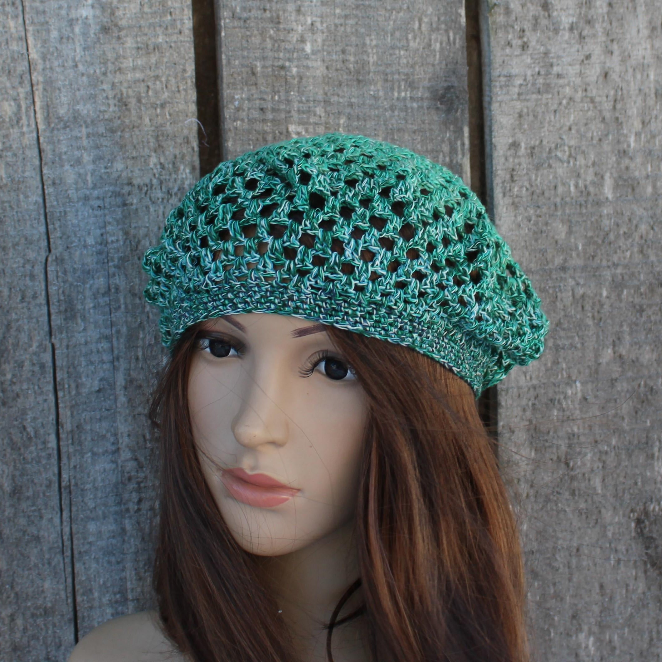 Green knitted hat on a mannequin head against a wooden background