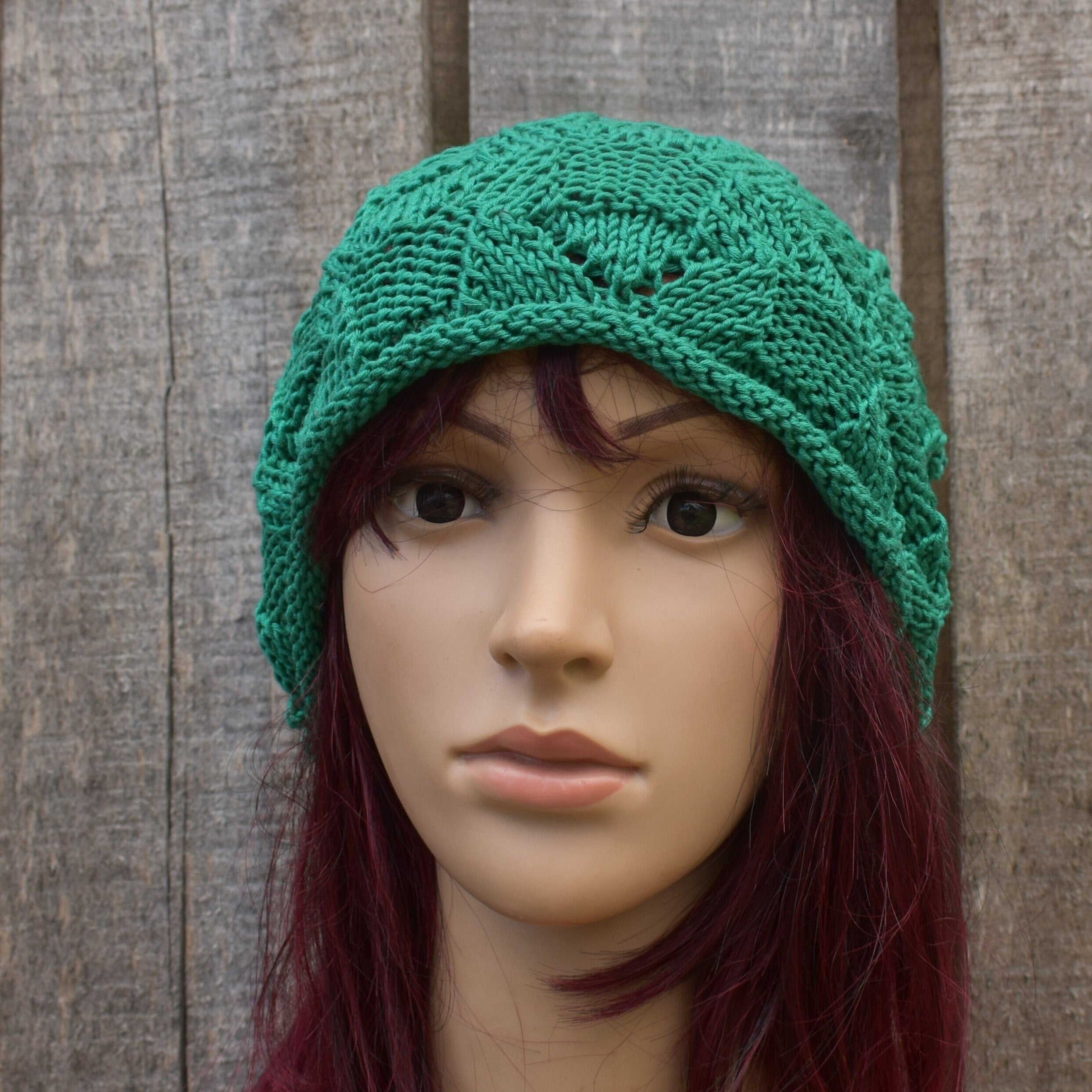 Green knitted hat on a mannequin head against a wooden background