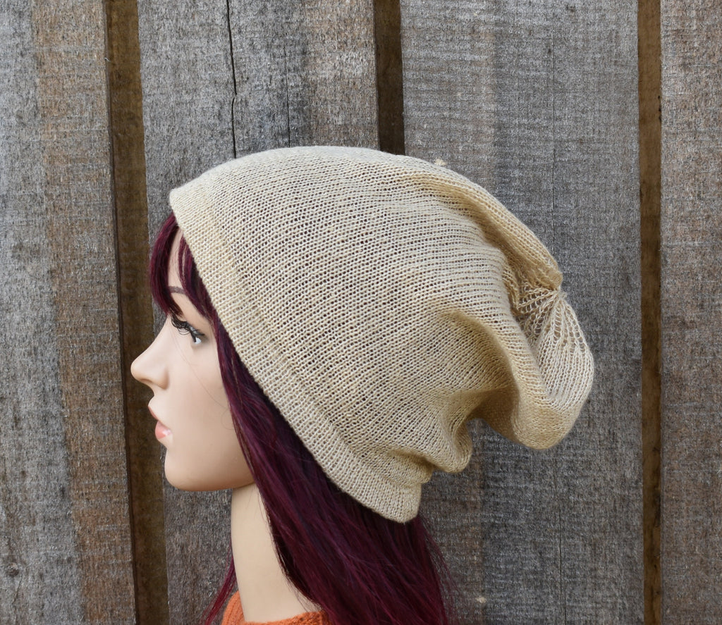 Beige knitted beanie on a mannequin head against a wooden background