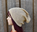 Beige knitted beanie on a mannequin head against a wooden background
