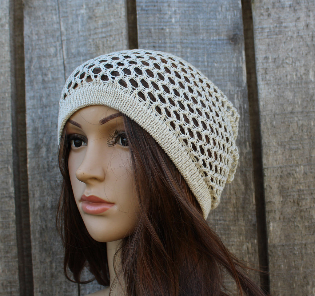 Mannequin head wearing a beige crochet hat against a wooden background