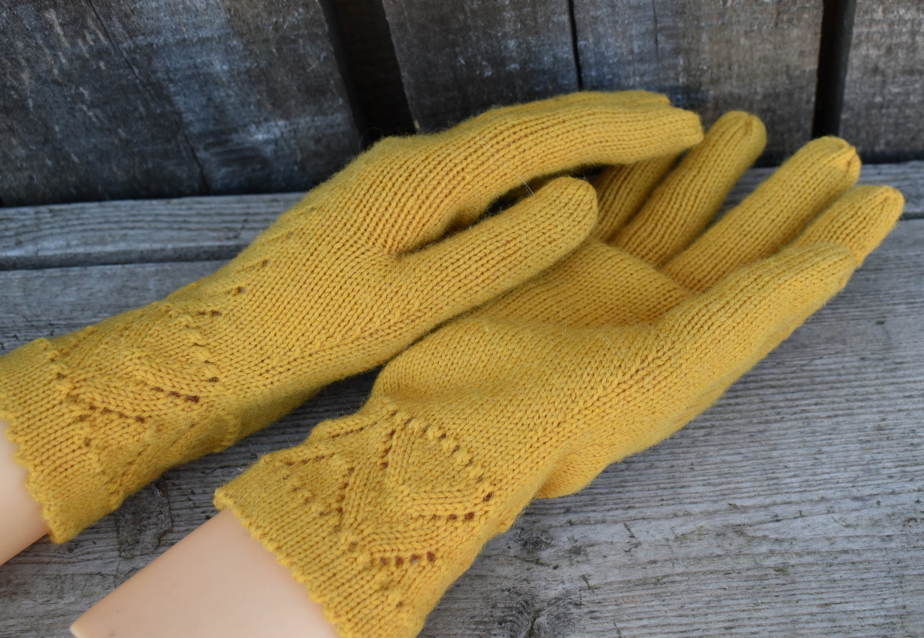 Pair of yellow knitted gloves on a wooden surface