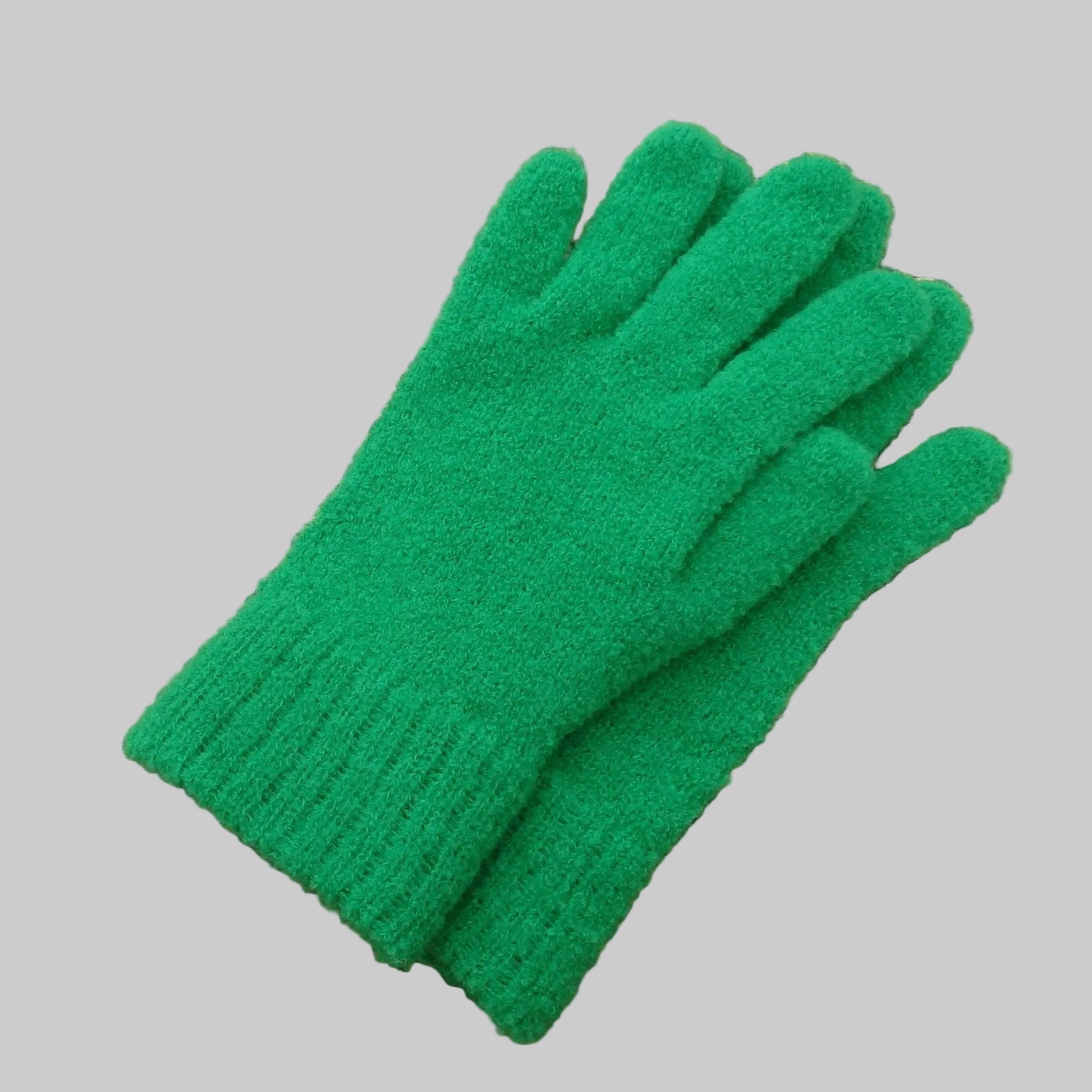 Knitted green gloves on a woven mat