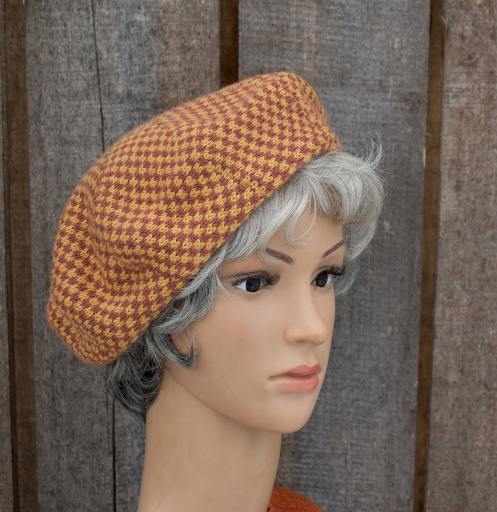 Mannequin head wearing a brown houndstooth patterned hat against a wooden background
