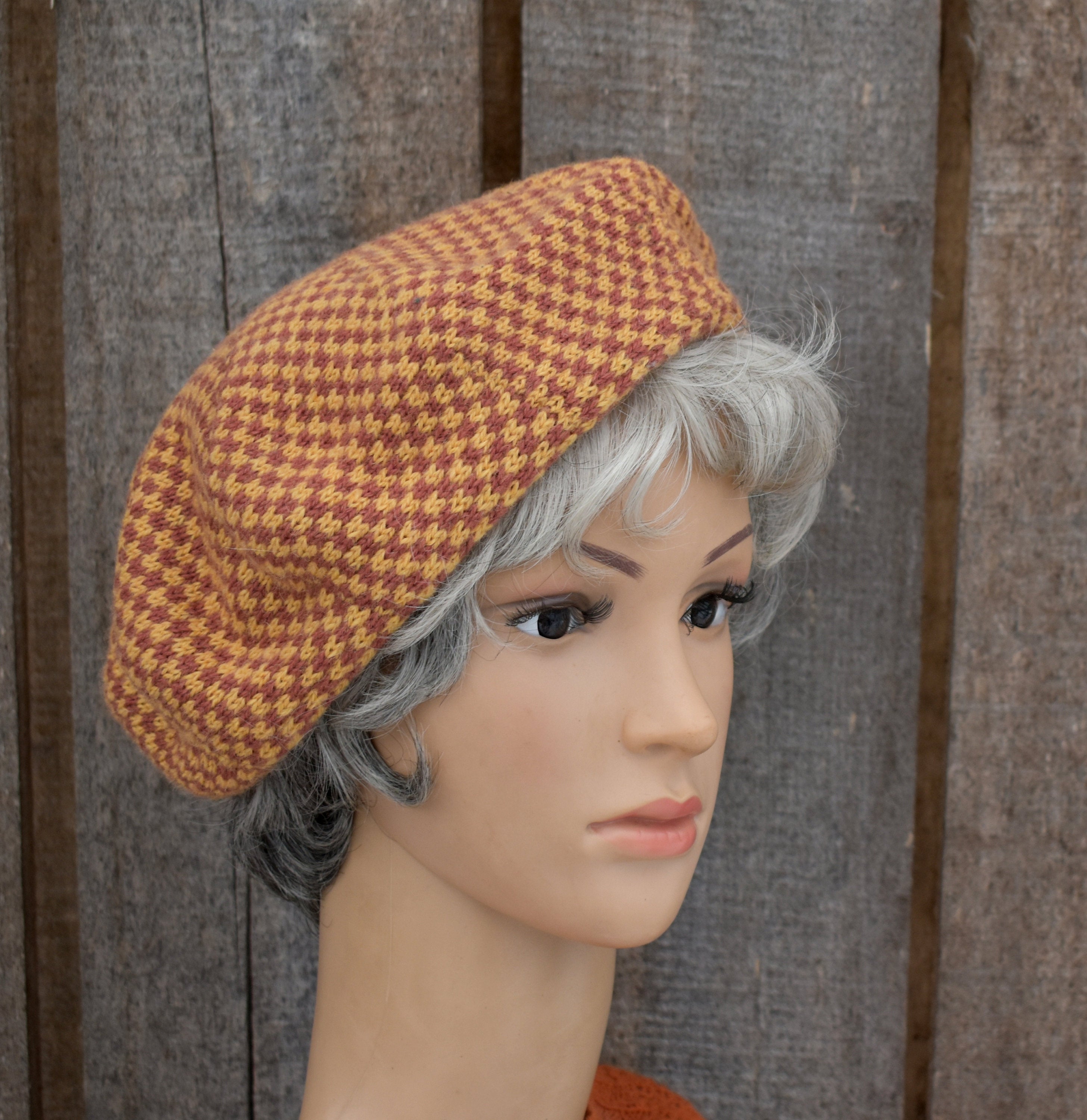 Mannequin head wearing a brown houndstooth patterned hat against a wooden background