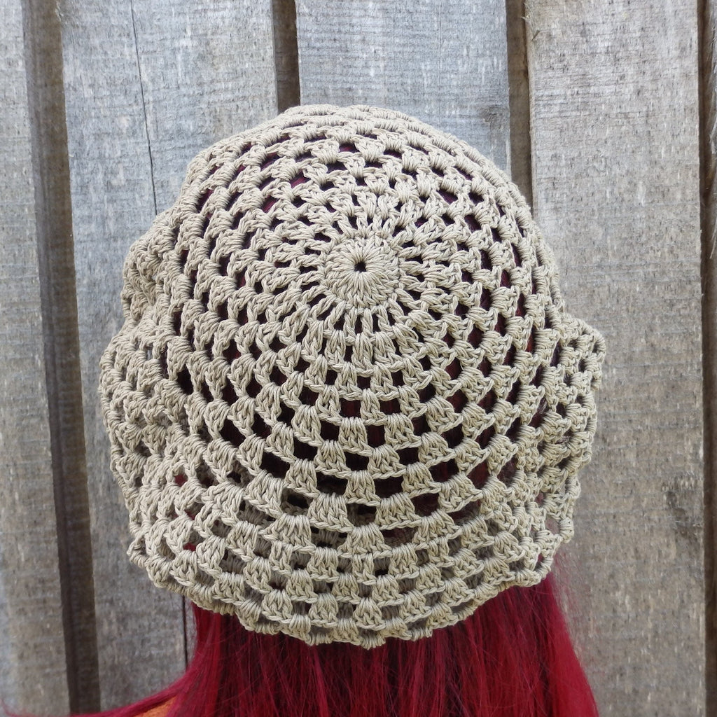 Beige crochet hat on a person with red hair against a wooden background