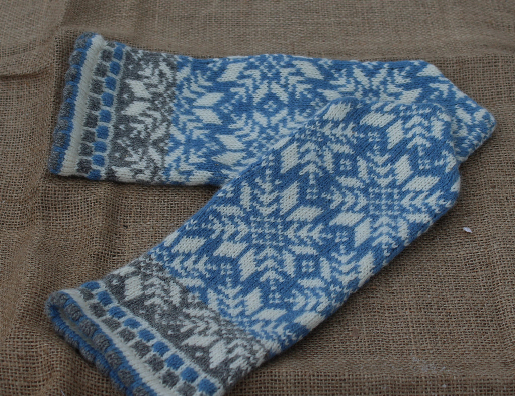 Blue and gray knitted mitten on a brown fabric background