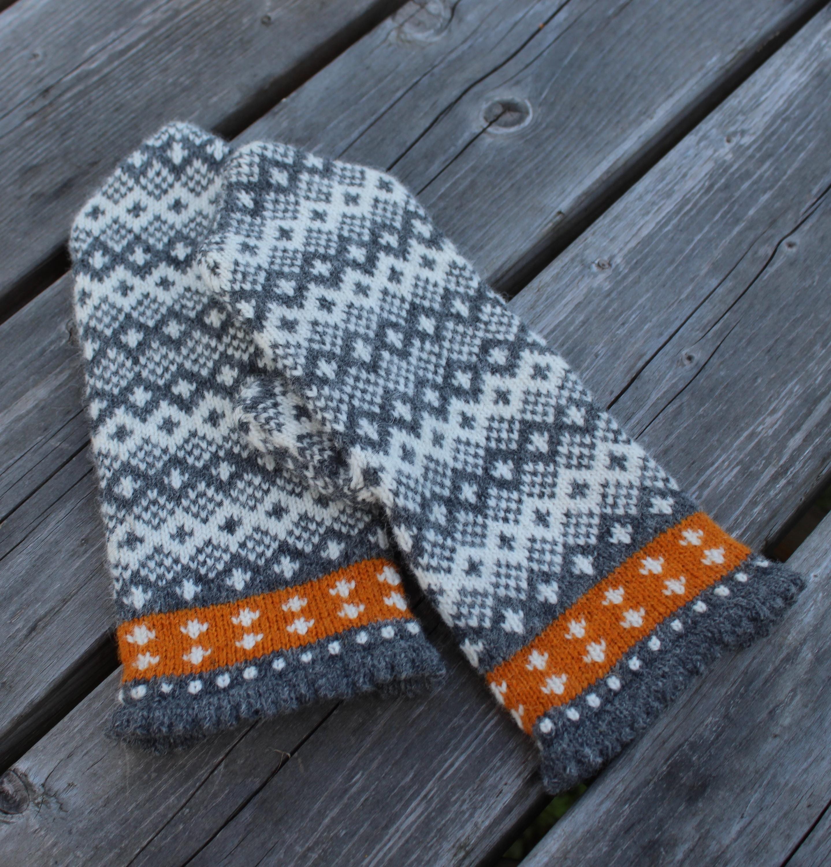 Pair of knitted mittens with a geometric pattern on a wooden surface