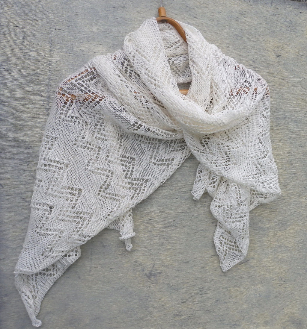 White lace shawl on a wooden hanger against a gray background