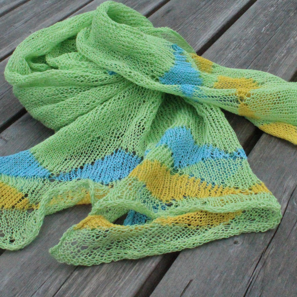 Knitted scarf with green, blue, and yellow pattern on a wooden surface