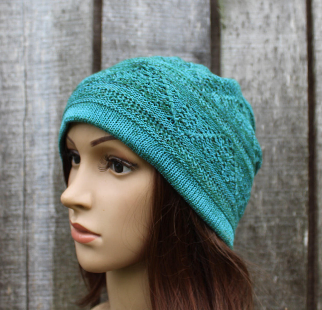 Teal knitted hat on a mannequin head against a wooden background
