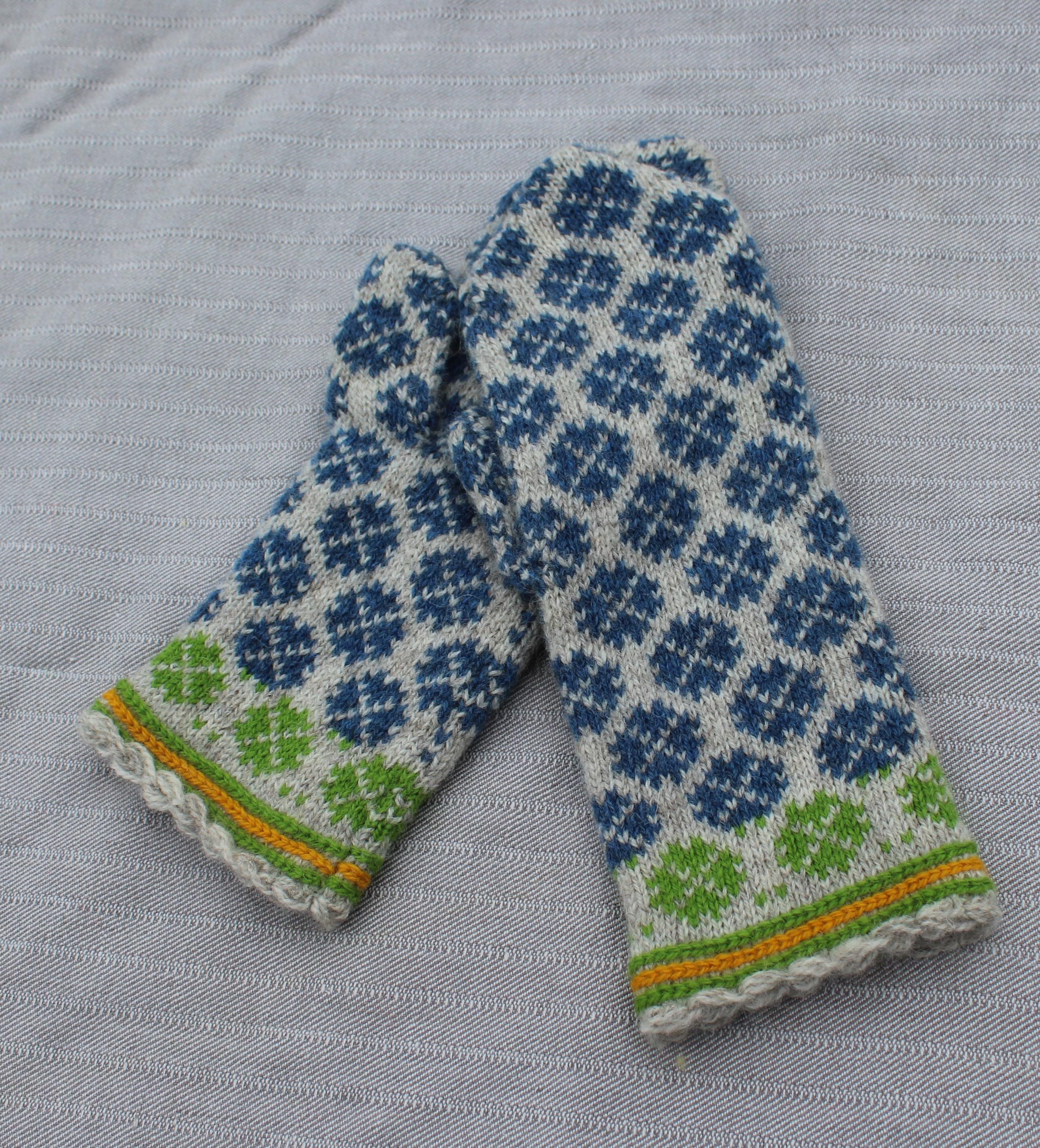 Pair of knitted mittens with a blue and white pattern on a gray fabric background