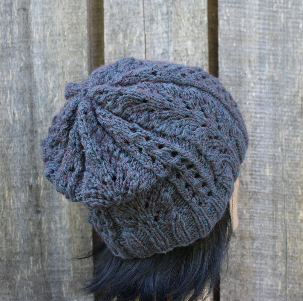 Blue knitted beanie on a person against a wooden background